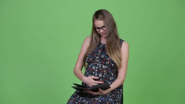 Young Happy Pregnant Woman Reading Book alt