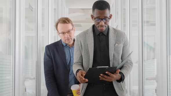 Two Men of Different Races and Ethnicities Walk in Office and Discuss Business