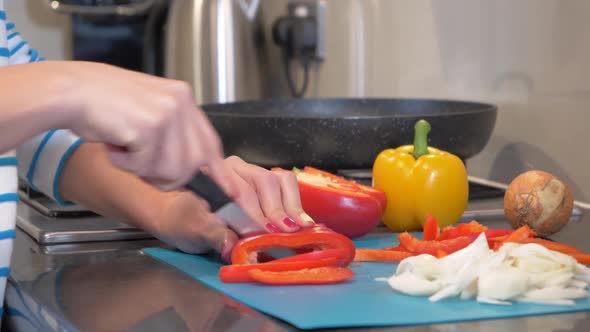 Woman cutting red bell pepper on chopping board