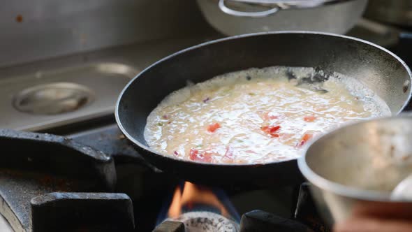 Cook prepares a masala omelet in a small metal bowl, mixes eggs with a fork.