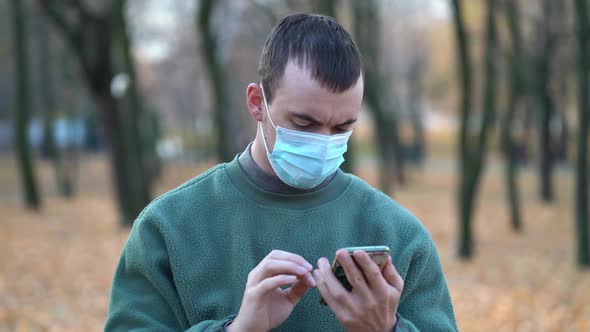 Man in a Protective Mask on His Face Used Smartphone
