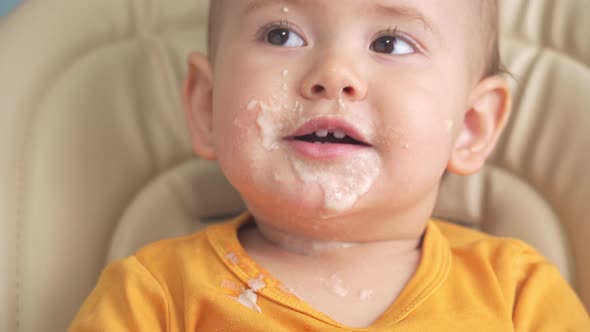 Toddler 12-18 months old eats oatmeal porridge and turns over his plate. alt