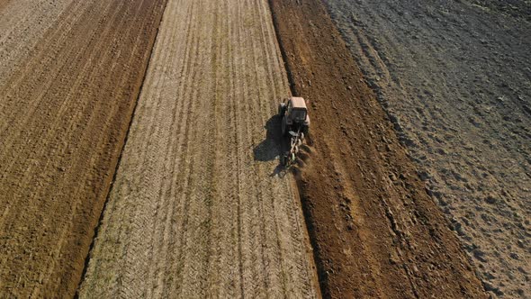 Tractors-agricultural Unit Performs the Plowing, the Cultivation of the Soil of Brown Color in the alt