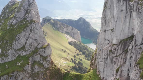 Flying past high mountain top, revealing a beautiful valley with a stunning lake alt