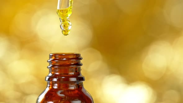 Super Slow Motion Shot of Oily Essence Drop Into Phial on Golden Background at 1000Fps alt