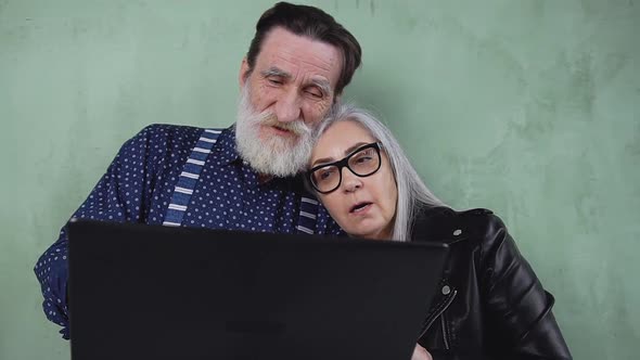 Modern Mature Couple which Standing Together Cuddling to Each other while Browsing the Text alt