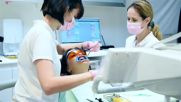 Dentist With Assistant Prepares Patient For Teeth Whitening Procedure