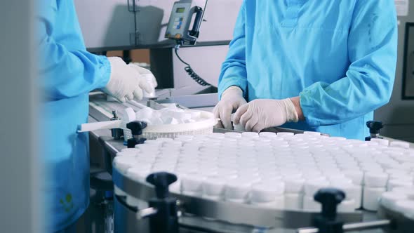 Factory Workers are Manually Closing Tubs with Pills alt