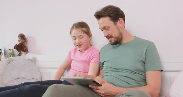 Father and Teen Daughter Sitting on the Sofa in Living Room Browsing the Online Store Enjoying alt