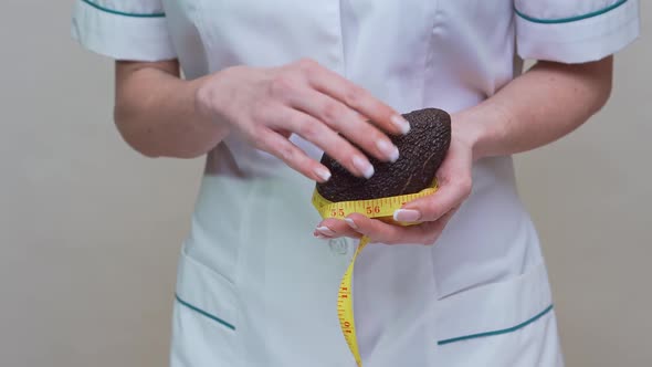 Nutritionist Doctor Healthy Lifestyle Concept - Holding Organic Avocado Fruit and Measuring Tape alt