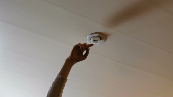 A Woman's Hand Knocks Against Energy-saving Light Bulb To Turn On