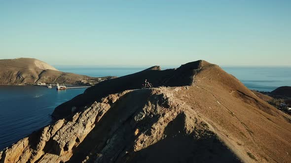 Drone View of Man on Motorbike Extremely Rides Across the Hills with Black Sea on Background in