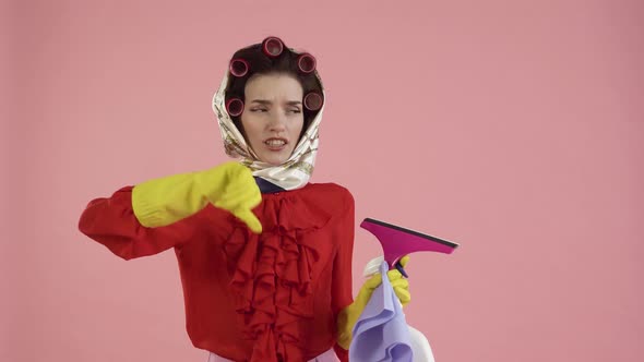 A Young Female Cleaner Shows a Dislike Gesture and Looks at the Camera