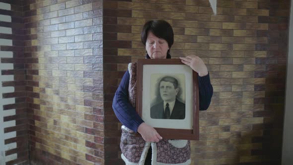 Senior 60s Woman Looking at Old Photo Portrait of an Ancestor