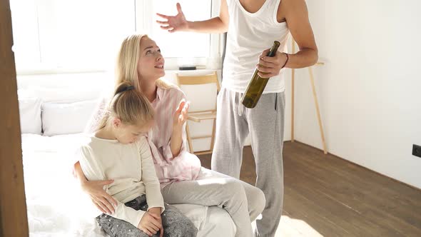 Drunk Father with an Empty Bottle in His Hand Yells at His Wife and Child
