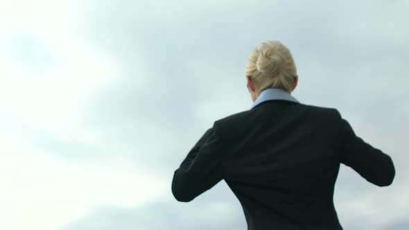 Female in Business Suit Raising Hands in Victory Gesture on Sky Background, Free