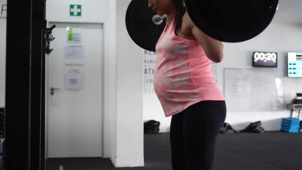 Footage of a pregnant female model doing squats in a gym trying to keep fit in her fourth trimester alt