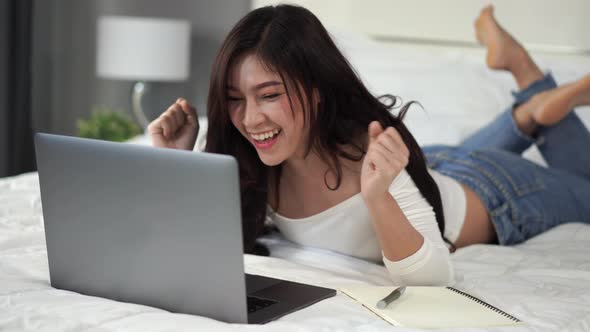surprised woman using a laptop computer on bed