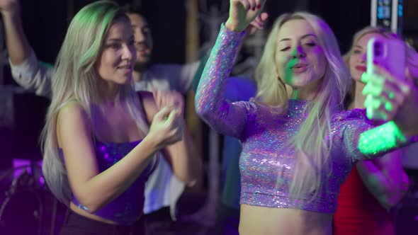 Beautiful Happy Caucasian Female Blogger Filming Leisure in Night Club on Smartphone Dancing with alt