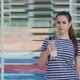 Sports Woman is Drinking a Water From a Shaker on the Background of Sports Equipment - VideoHive Item for Sale