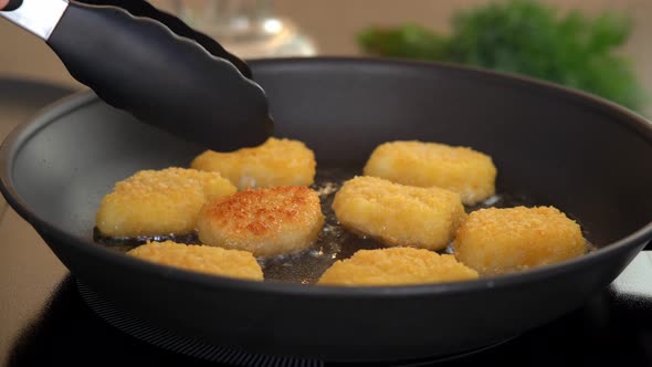 Kitchen Tongs Flip Fried Chicken Nuggets in Sizzling Oil in Hot Frying Pan