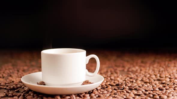 Steam Rises From a Mug of Hot Coffee Against a Background of Roasted Coffee Beans alt