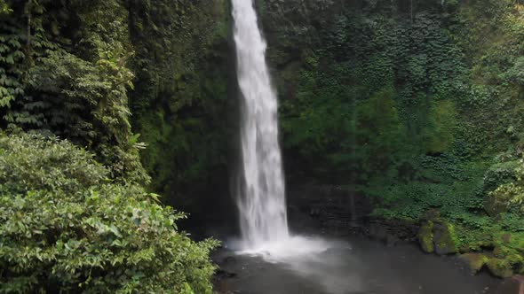 A drone captures the power and magnificence of the Nungnung Waterfall as it rises to the top of the alt