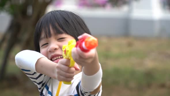Cute Asian Child Playing With Water Gun In The Summer alt