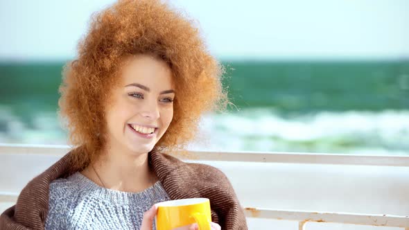 Beautiful Pensive Redhead Woman at the Beach Drinking Tea