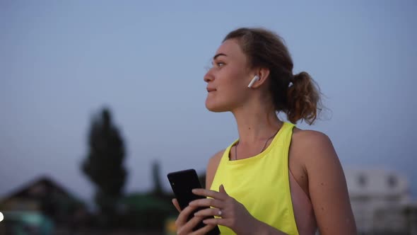 Happy Young Woman Chatting in Smartphone in the Headphones