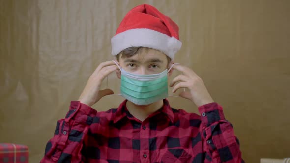 Guy in Santa Claus Hat Puts on His Face Medical Mask