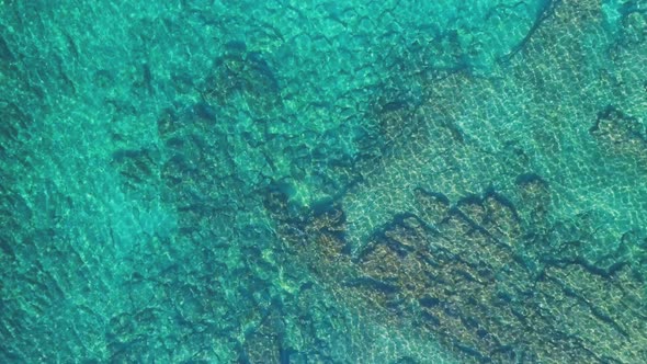 Transparent sea water near stony remote coast alt