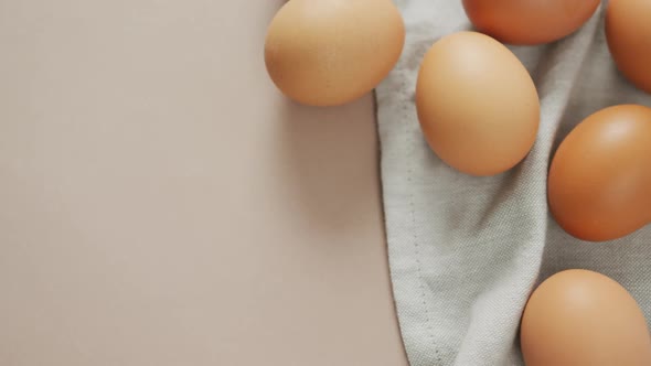 Video of overhead view of eggs and on rustic cloth on beige background alt