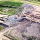 Drone circling in arc around large pile of rubbish at landfill site, surrounded by green vegetation. - VideoHive Item for Sale