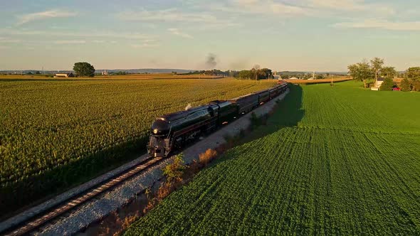Aerial View of a Steam Engine Puffing Smoke and Steam with Passenger Coaches Traveling alt
