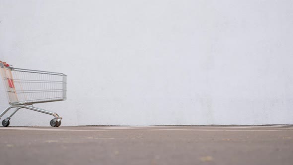 Guy in a Disposable Facemask Focused on the Phone Goes Near the Store. Shopping During the alt