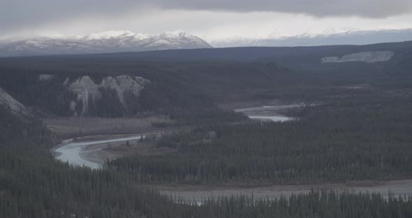 Aerial helicopter shot flying past houses on a hill, mountains in the distance, misty clouds, drone  alt