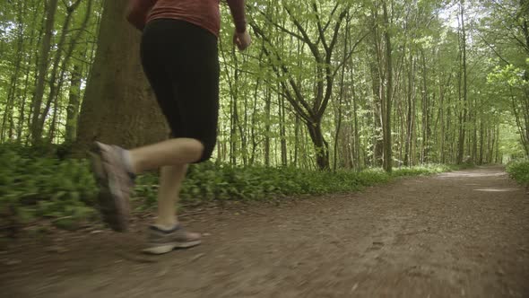 View of Woman's Legs in Black Leggings Sprinting By the Side of the Forest Path alt