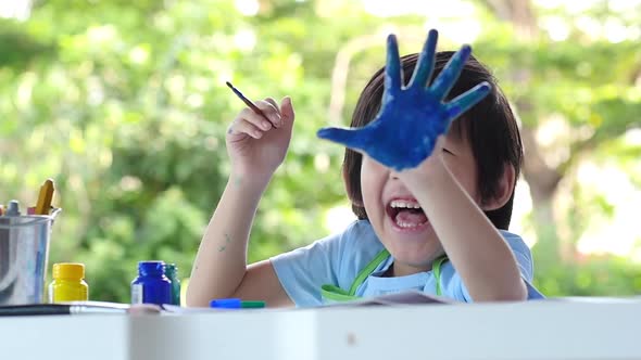 Cute Asian Child Enjoying Arts And Crafts Painting With His Hand alt