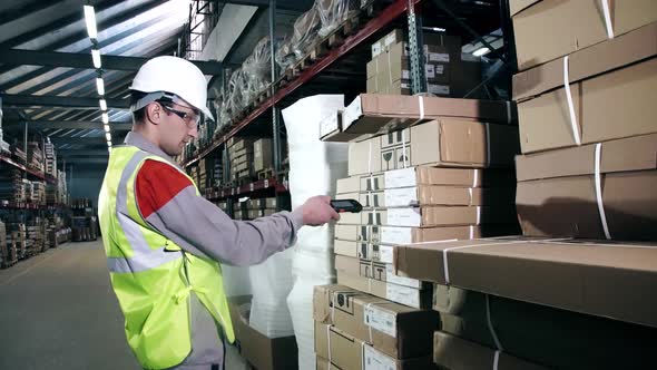 A Warehouse Worker in Protective Equipment Uses a Bar Code Scanner alt