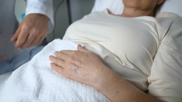 Male Doctor Holding Hand of Terminally Ill Patient, Worrying About Her Health