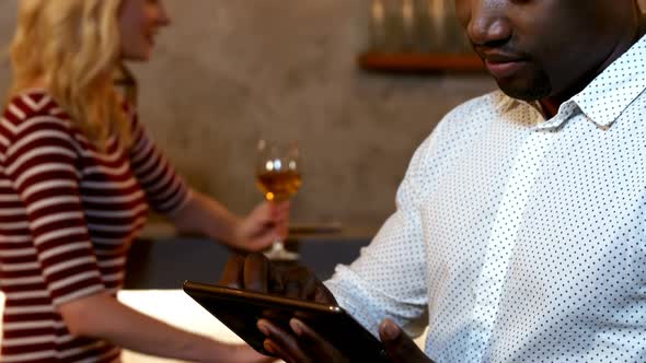 Man using his tablet while friends interacting in background 4K 4k alt