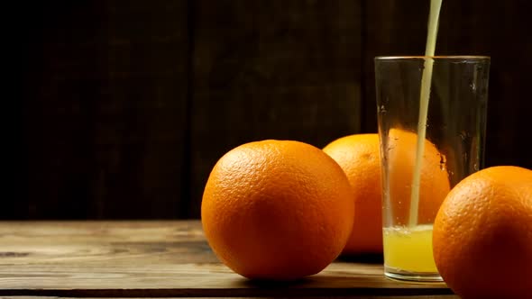 Pour Orange Juice Into A Glass And Three Oranges Next To Them On The Table