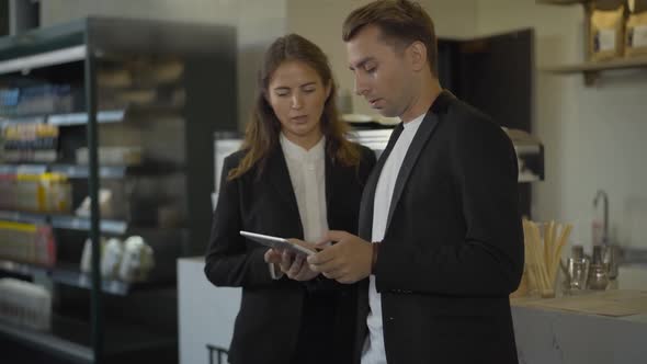 Confident Concentrated Business People Surfing Internet on Tablet and Talking While Waiting for alt