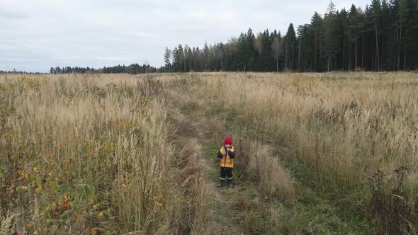 Boy Child in a Yellow Vest and Red Hat Runs alt