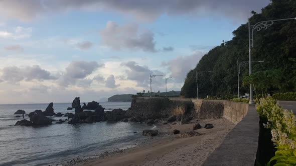 Mountain side road by the ocean and giant corals and thick clouds in Batanes, Philippines alt