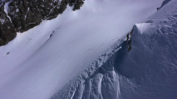 Aerial shot of Alpine Skiers walking up the mountain with ski's and poles for support