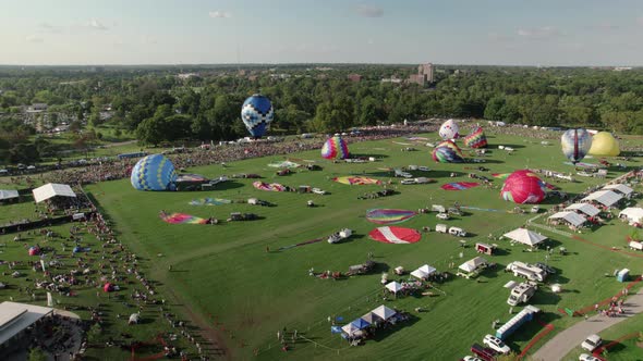 Aerial descent above Forest Park in St. Louis, hot air balloons starting race. alt