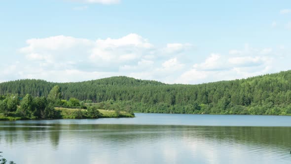 Beautiful Clouds Move Over a Body of Water and Wooded Mountains on a Summer Sunny Day alt