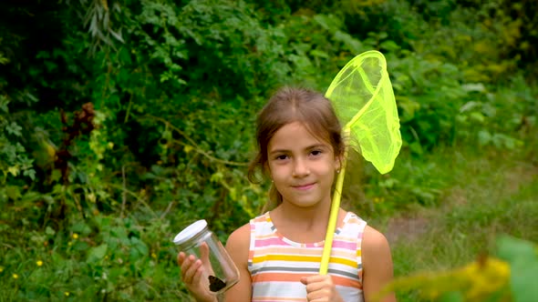 A Child Girl Catches Butterflies with a Butterfly Net alt